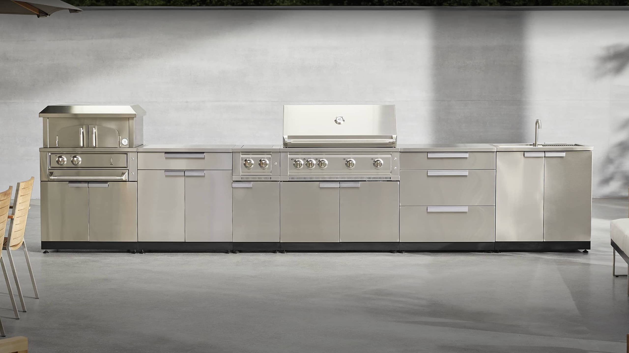 NewAge outdoor kitchen with stone-clad surrounds, a kamado grill and built-in gas grill
